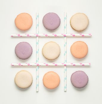 Creative concept photo of macaroons and straws as noughts and crosses game.