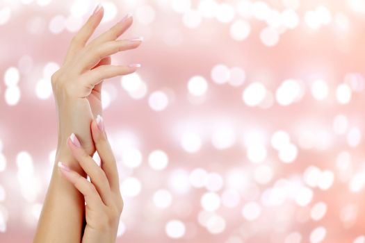 Beautiful woman hands against an abstract background with blurred lights