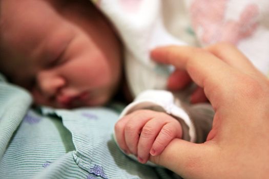 Sleeping newborn baby in the arms of my mother in hospital