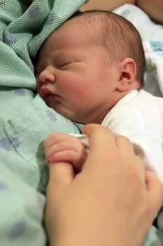 Sleeping newborn baby in the arms of my mother in hospital