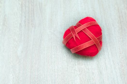 Ribbon wrapped heart on wood background