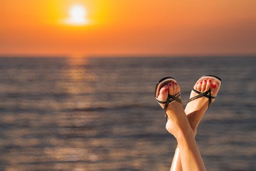 Woman' feet at the sea during sunrise