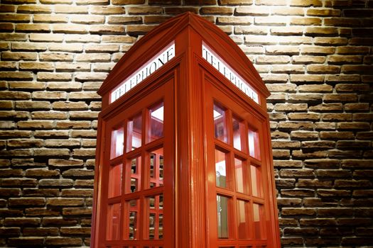 telephone booth against illuminated brick wall 
