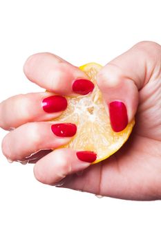 Hand with manicured nails painted a deep glossy red squeeze lemon on white background