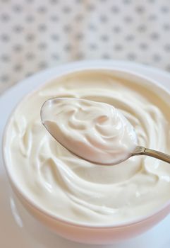 Ceramic bowl of white yoghurt in spoon