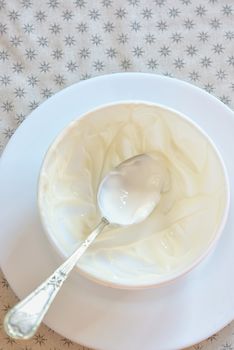 Emty ceramic bowl of white yoghurt and spoon