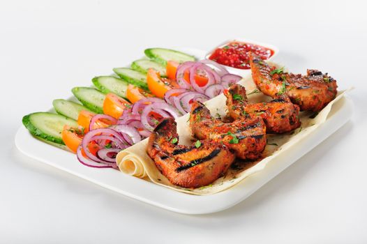 Grilled lamb tongues with fresh vegetables salad and hot sauce, top view