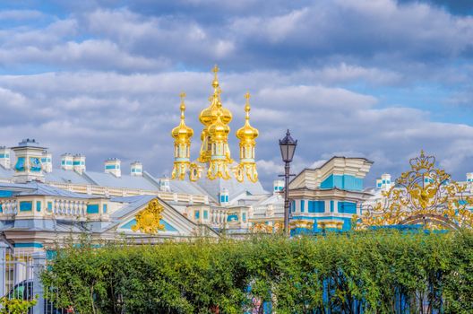 Catherine Palace in Pushkin with golden domes and blue walls illuminated by the afternoon sun
