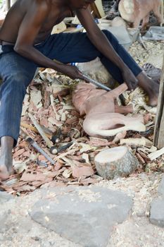 Kenyan craftsman carving two lions with pink wood in a cooperative in Mombasa