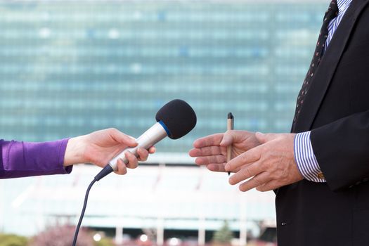 Reporter interviewing businessman, corporate building in background