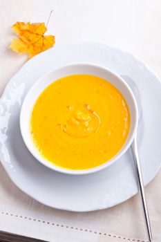 Pumpkin creme soup with a spoon served on a table