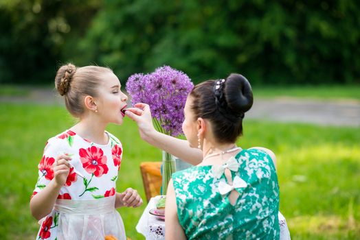 mother with daughter have a breakfast in the garden