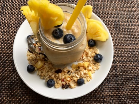 Breakfast with granola, yogurt and blueberries. Muesli and berries on the white plate, yogurt in the glasses jar.