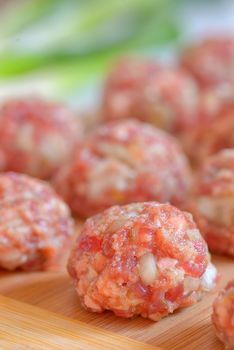 Raw Uncooked Meatballs on wooden plate