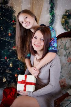 Daughter hugging mother under Christmas tree