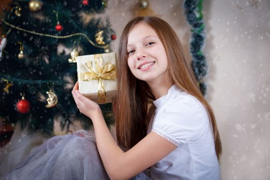 Pretty girl with gift box under Christmas tree