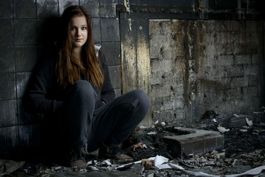 Portrait of a young girl sitting in a house what is destroyed by fire