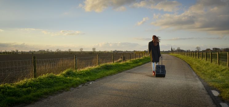 runaway girl standing with her suitcase on the road and look for the last time to her native village