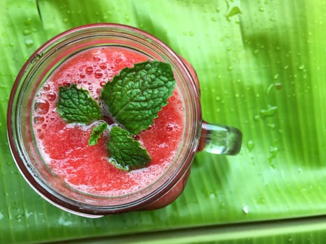Closeup of fresh juice with watermelon and mint leaf on the banana leaf.