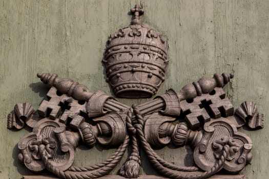 the emblem of the Vatican on green door of the church