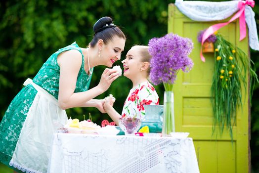 mother with daughter have a breakfast in the garden