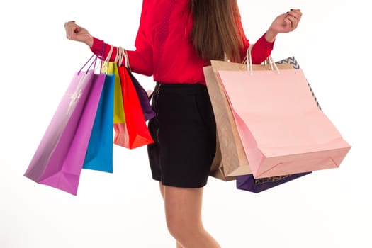 Woman holds her purchases, many colorful paper bags, packages, in her arms after shopping