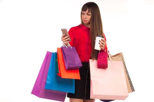 Young woman with credit card, colourful shopping paper bags and packages, smartphone, coffee paper glass