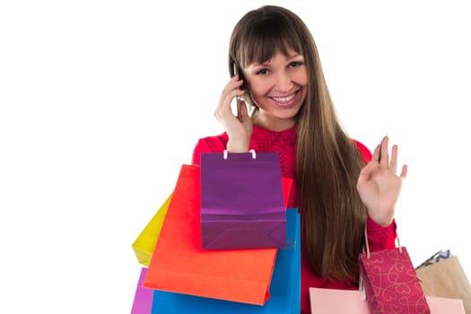 Young woman shopping with credit card holding colourful paper bags and packages talking on smartphone