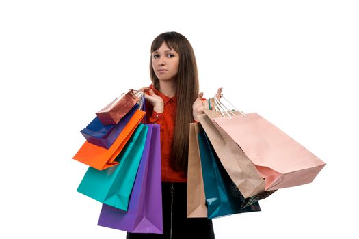 Young long-haired woman holds her purchases, many colorful paper bags, packages in her hands after shopping