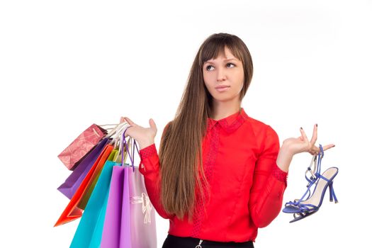 Young long-haired woman holds her purchases, many colorful paper bags, packages, and shoes in her hands after shopping