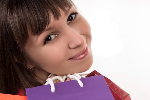 Close-up of smiling young woman face with colourful shopping paper bags