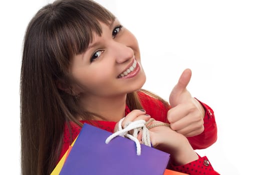 Smiling young woman at shopping with colourful bags shows a good sign with her finger