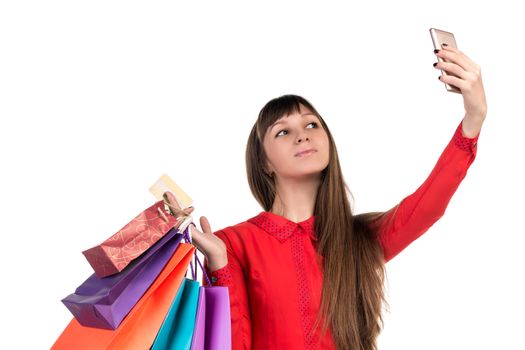 Young woman shopping with credit card holding colourful paper bags and packages does selfie