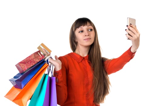 Young woman shopping with credit card holding colourful paper bags and packages does selfie