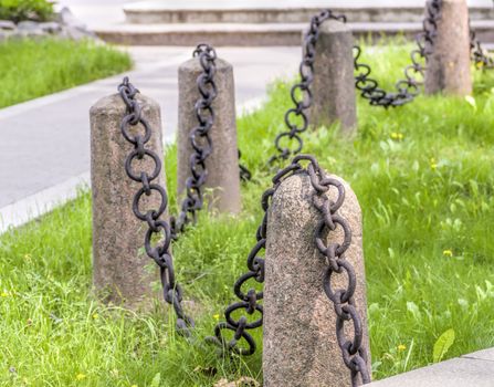 granite pedestal with a chain on a background of green grass old guard