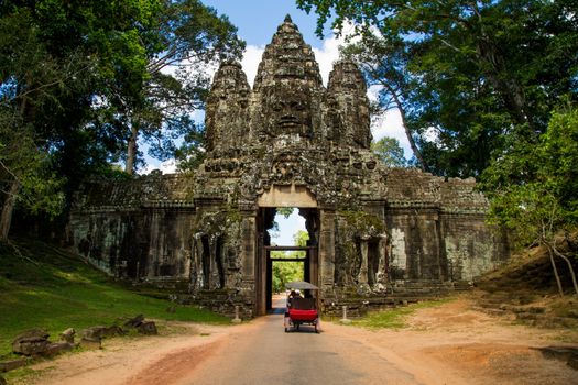 Ankor wat temple wall with tuk tuk on a road