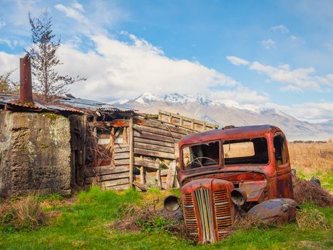 A ruined classic car with mountains behind it