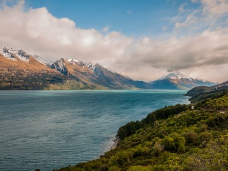 Blue lake with cloudy sky and snowcaped mountains