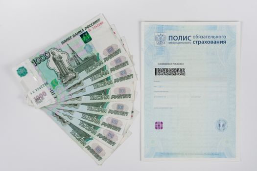 Next to the health insurance policy is a fan of thousand-pack of banknotes, white background