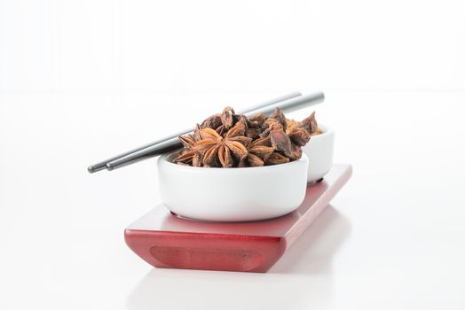 Small white bowl filled with whole aniseeds.