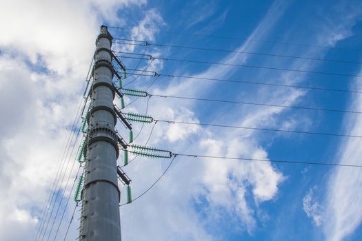 High-voltage power lines and insulators over blue sky background