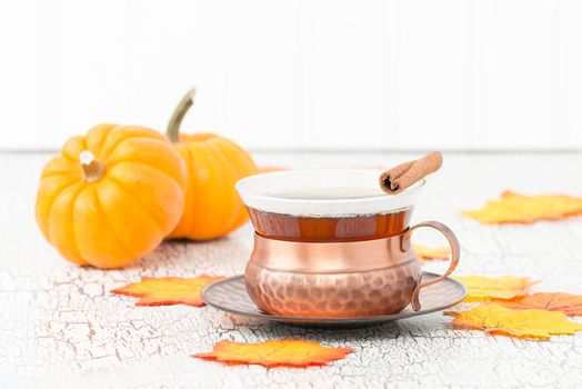 Cup of fresh brewed chai tea with fall leaves.