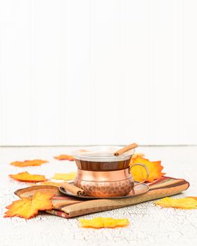 Cup of hot chai tea with colorful autumn leaves.