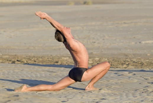 man training in yoga on the beach