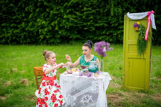 mother with daughter have a breakfast in the garden