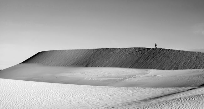 Life is the trip, lonely man enjoy calm scene on Vietnamese sand hill, sandhill with amazing shape in black and white tone in summertime, adventure travel in the choice of freedom young people