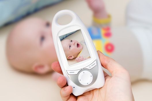 Hand holding video baby monitor for security of the baby