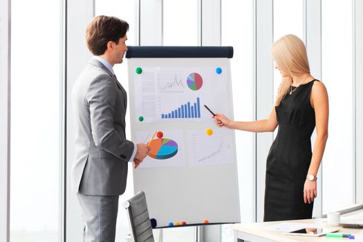 Workers at business meeting looking at presentation of financial reports in modern office