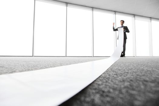 Office worker unrolling long sheet of paper