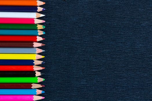 Black background for presentation with vertical colourful right border of multicoloured wooden pencils